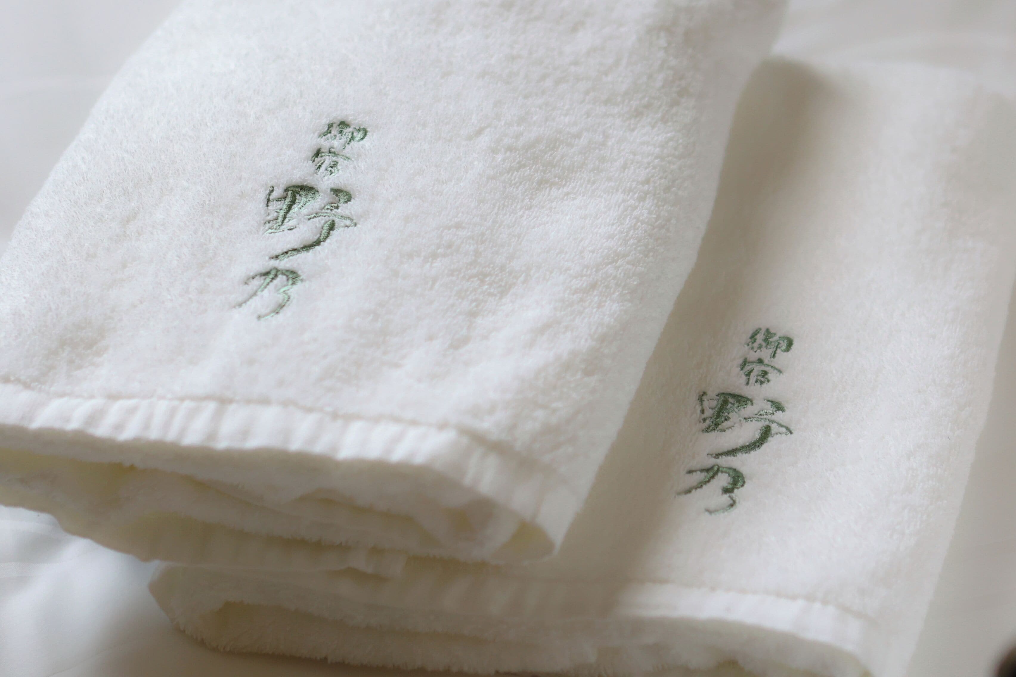 A stack of white towels with embroidered text.
