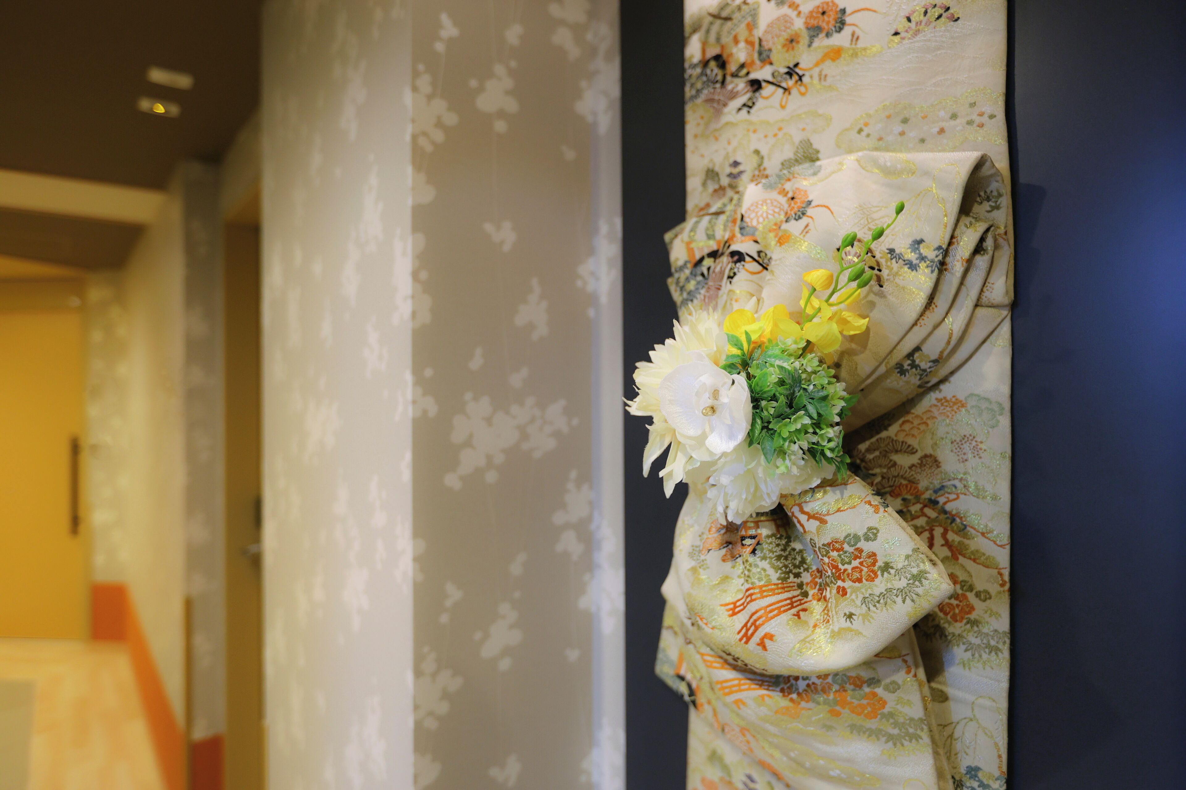 A room with floral wallpaper and a decorative floral arrangement on a wall.