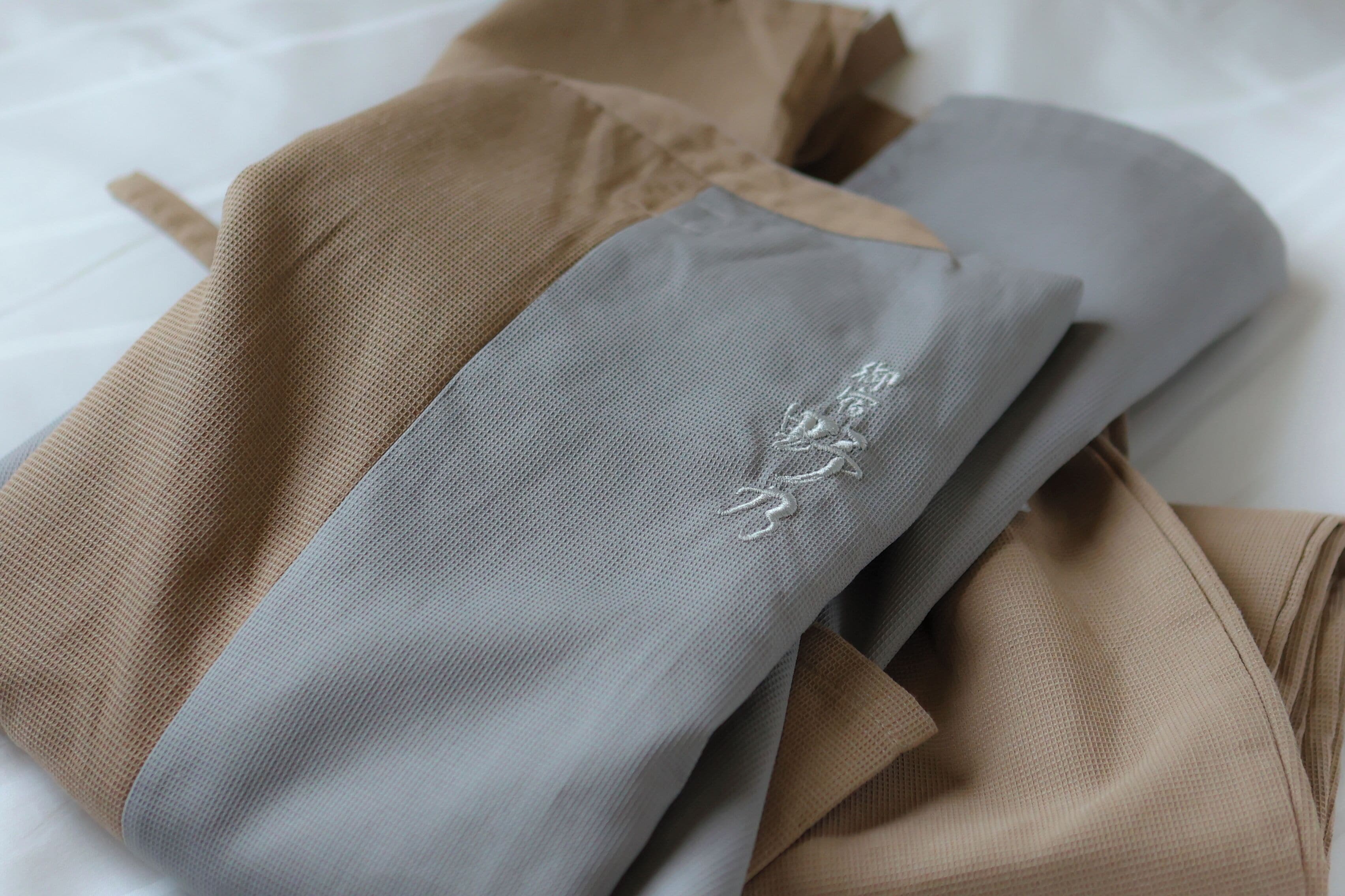 Ein Bett mit ordentlich gebetteter Bettwäsche in Beige und Grau.