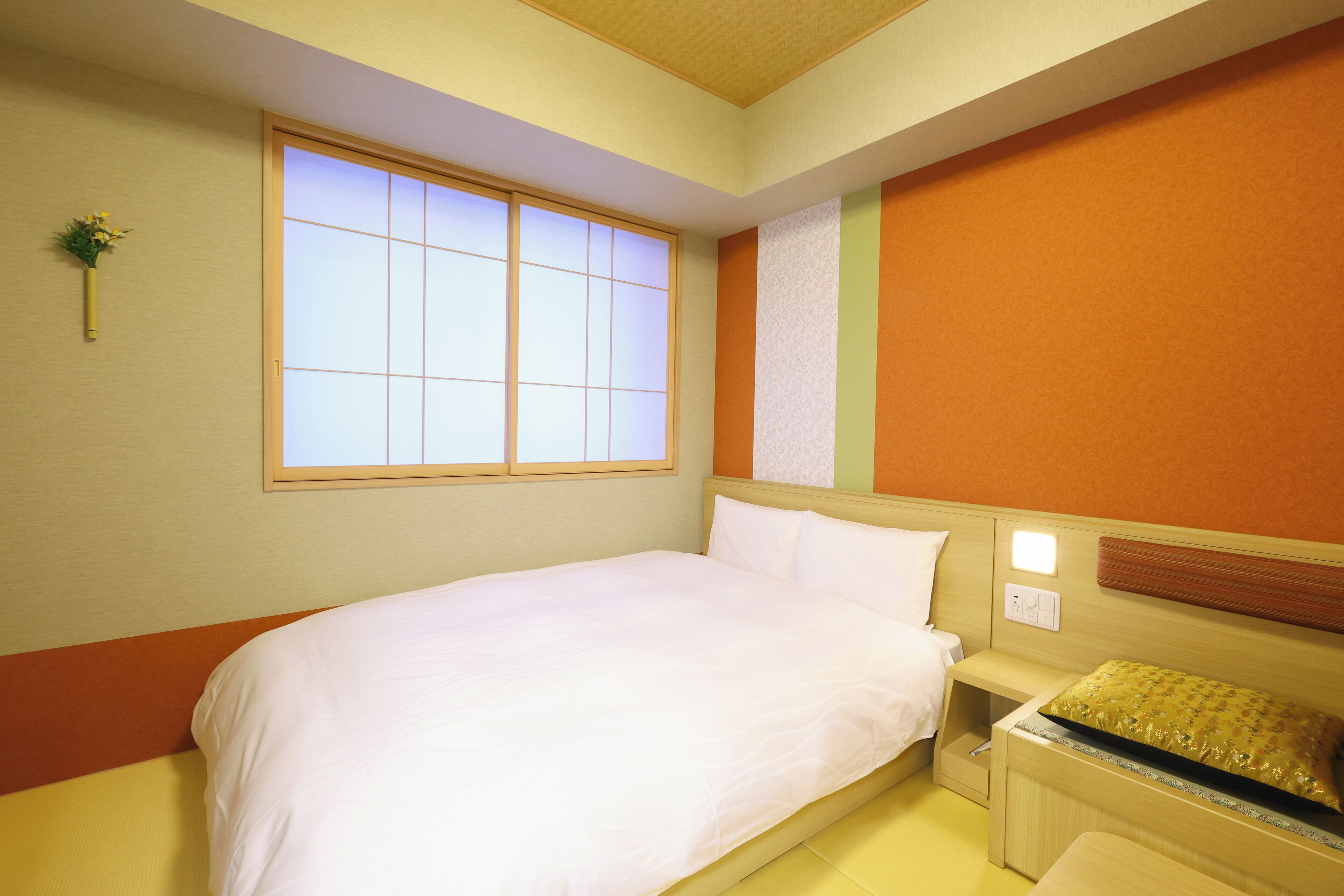 A hotel room with a bed, bedside table, and a window with a view.