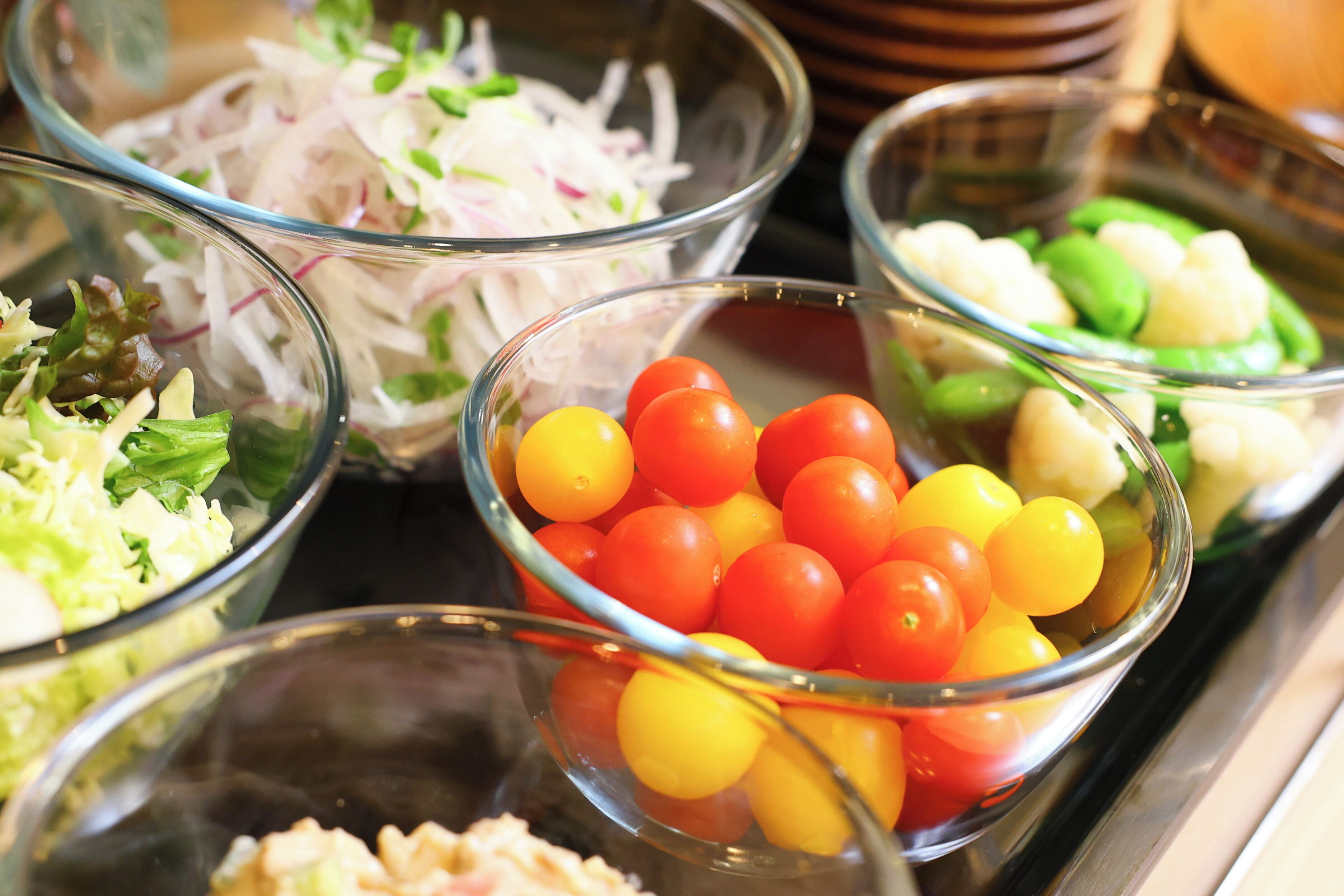 A variety of food items in glass bowls, including sliced vegetables and cherry tomatoes.