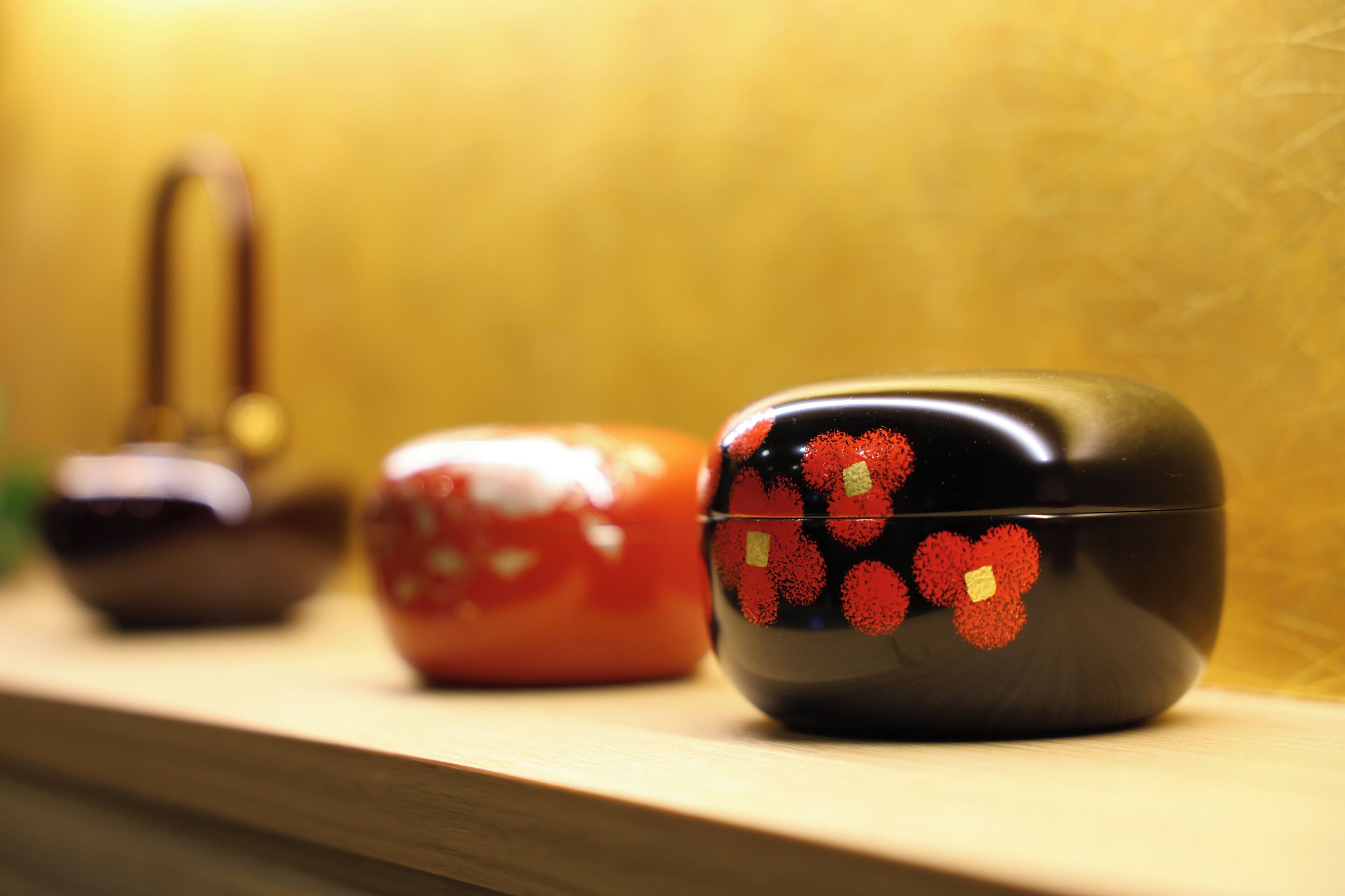 A row of three decorative containers on a wooden surface.