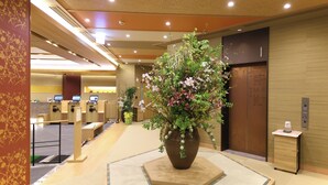 Un área de recepción con un gran arreglo floral, un mostrador de recepción y un ascensor.