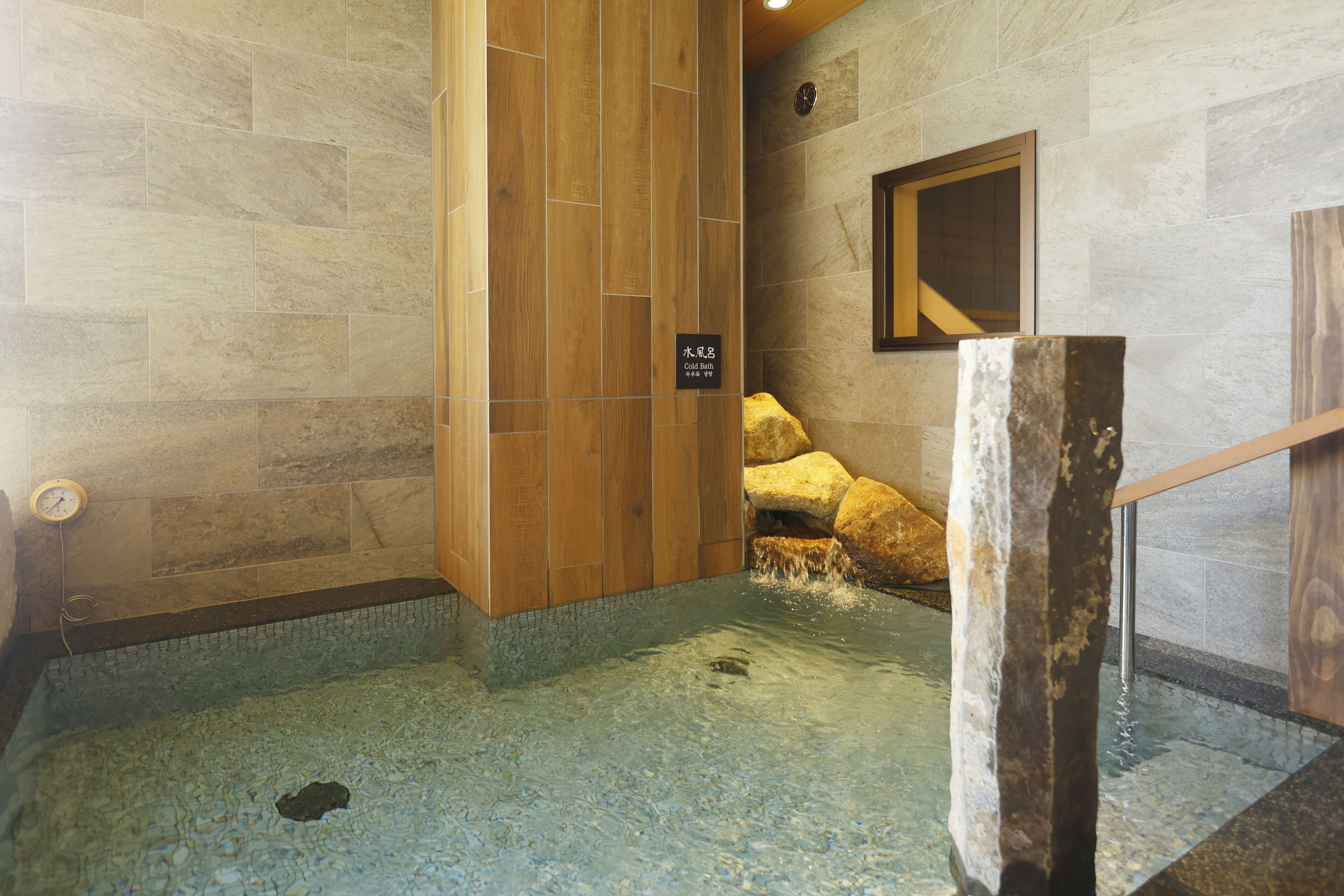 Ein Badezimmer mit Steinwänden, einer Holzverkleidung und einem Schild, das auf eine Thermalquelle hinweist.
