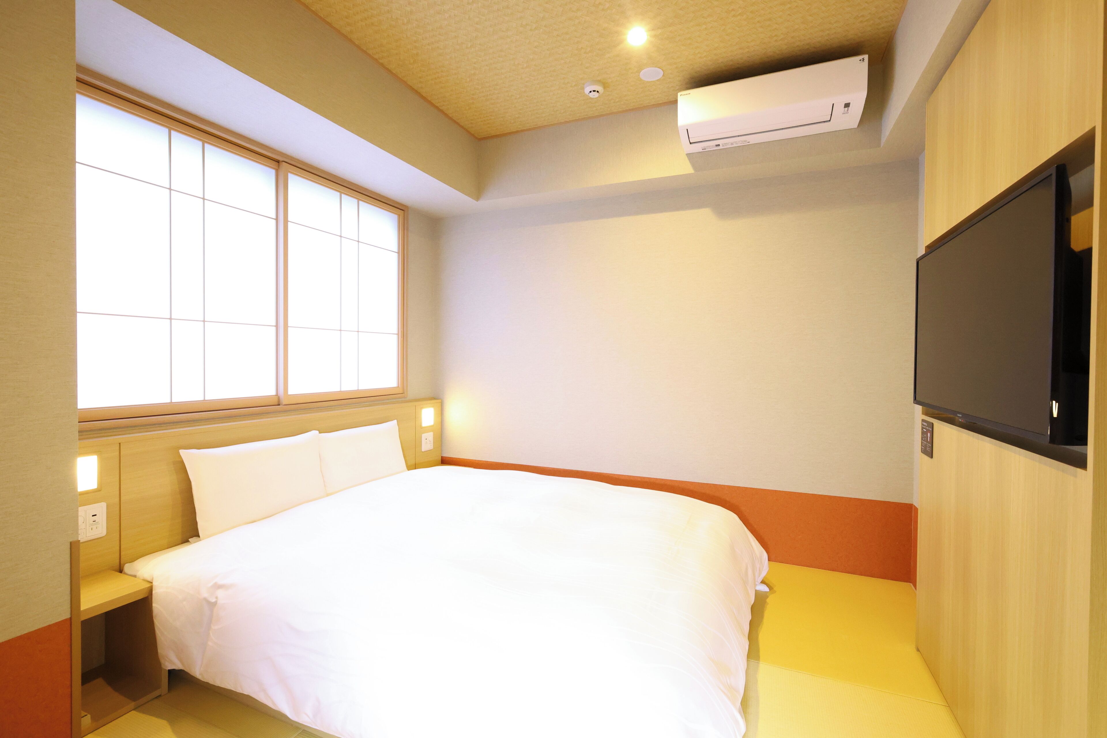A hotel room with a bed, a TV, and a window.