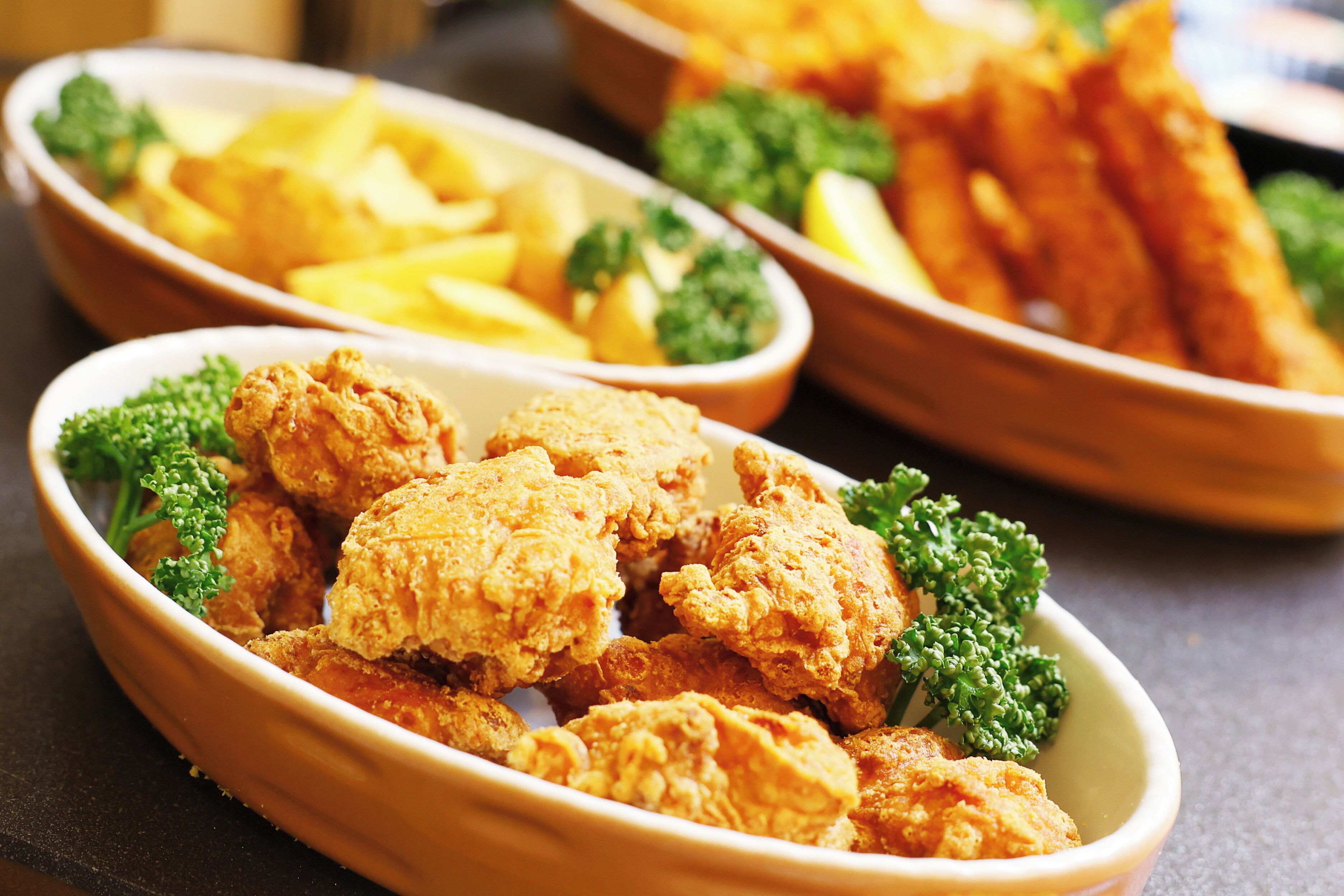 A bowl of fried chicken with fries and broccoli.