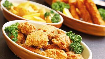 A bowl of fried chicken with fries and broccoli.