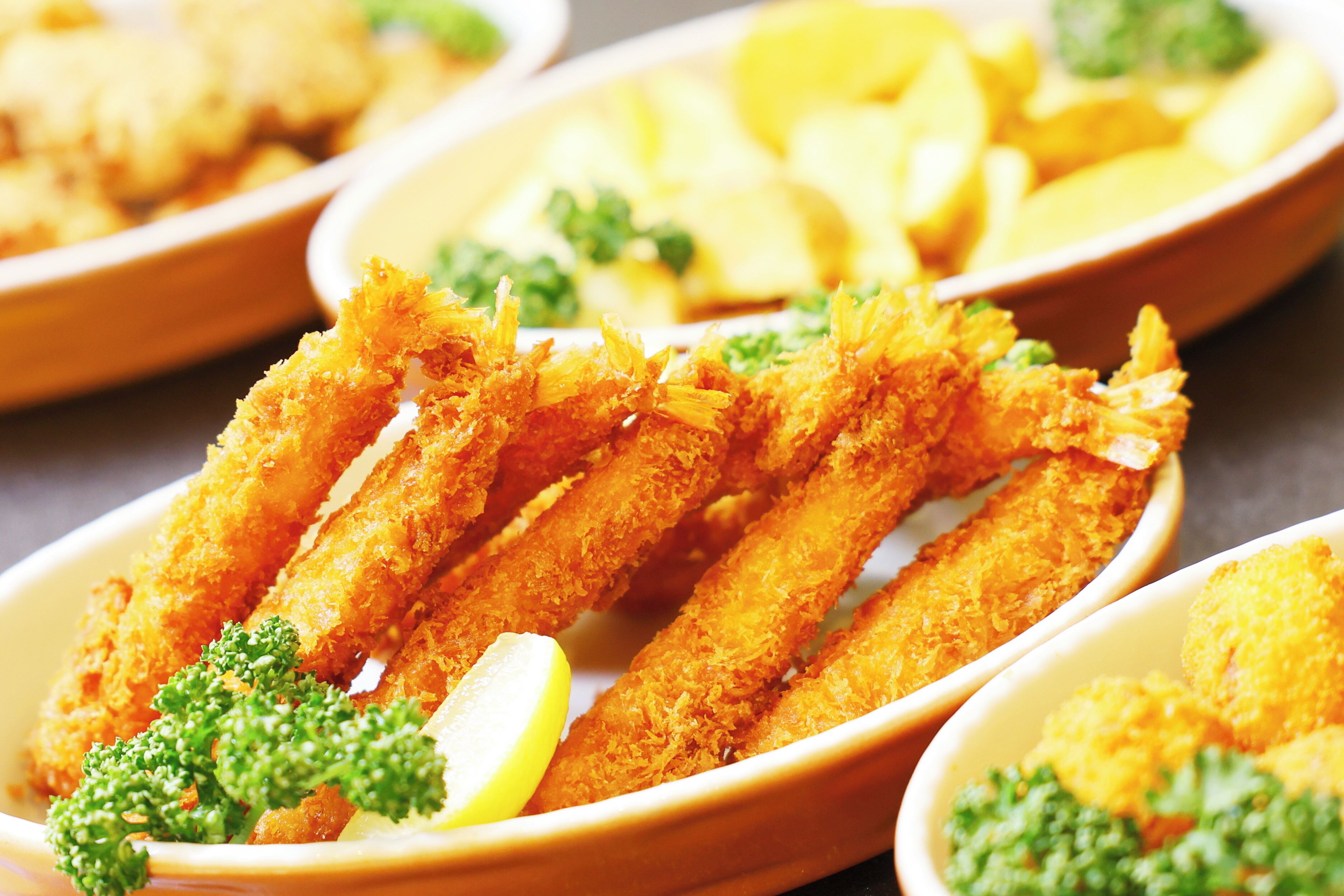 A close-up of breaded and fried food items, likely chicken tenders, garnished with parsley and lemon slices.