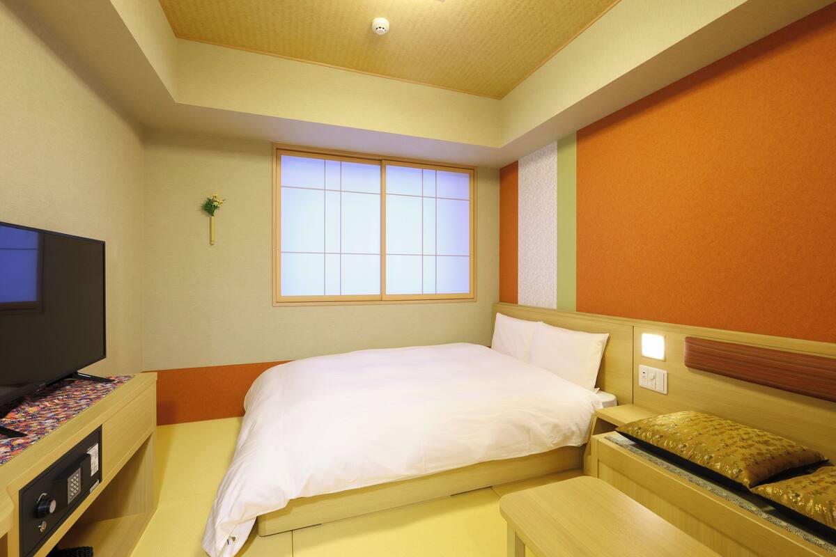 Ein Hotelzimmer mit Bett, Nachttisch, Fernseher und einem Fenster mit Blick.