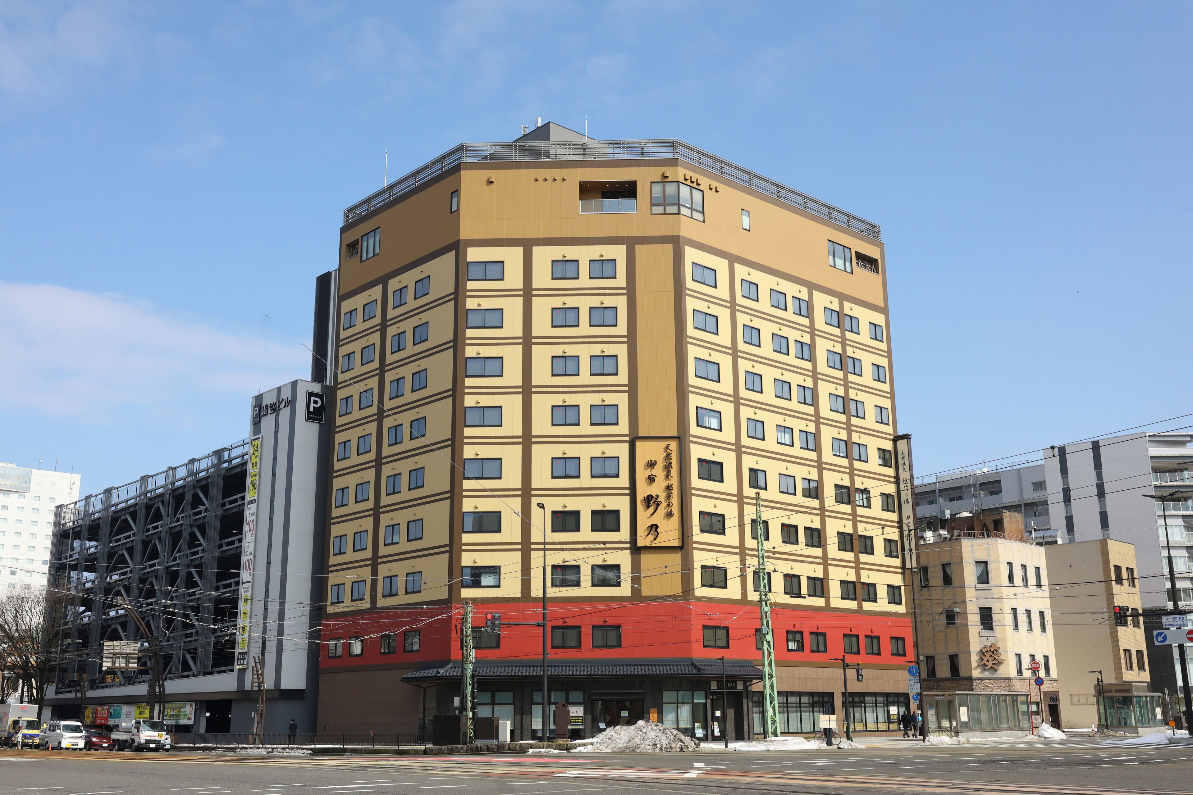 A multi-story hotel with a yellow facade, multiple windows, and a red lower section.