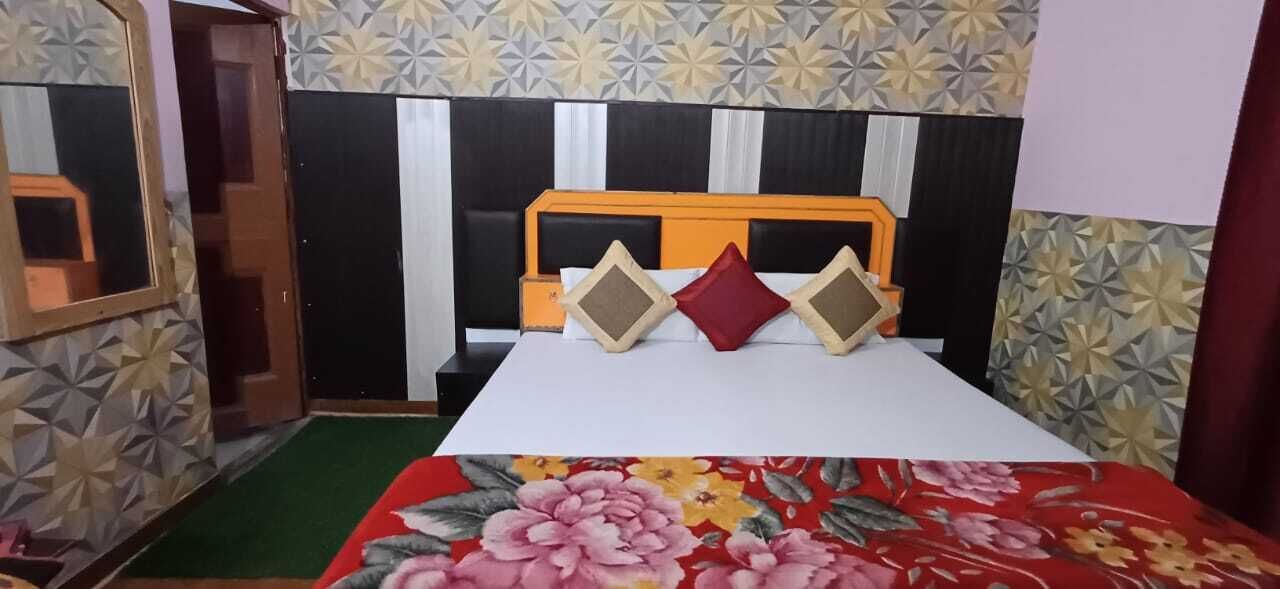 A bedroom with a bed, a headboard, and a floral-patterned wall.