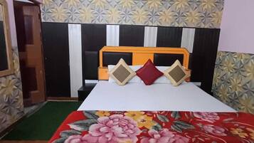 A bedroom with a bed, a headboard, and a floral-patterned wall.