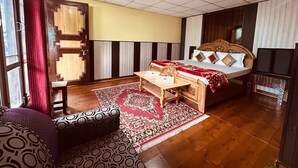 Een hotelkamer met een bed, een houten bureau, een stoel, een bank en een kamerbreed tapijt met een patroon.