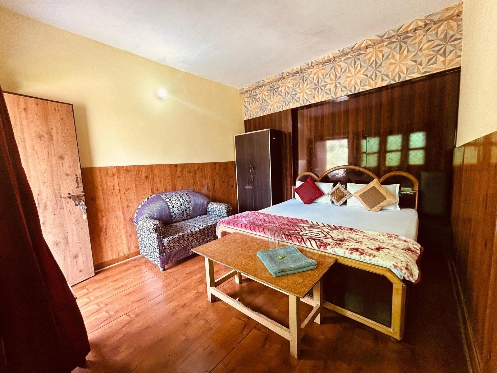 Un dormitorio con cama, una silla de madera, una mesita y un armario.