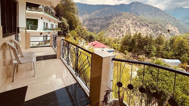 Een balkon met uitzicht op een bergachtig landschap, een gebouw met een rood dak, en een bordje met de tekst 'Hotel House'.