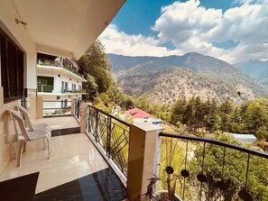 A balcony with a view of a mountainous landscape, a building with a red roof, and a sign that reads "Hotel House".