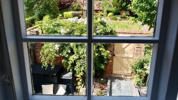 A window with a view of a garden and a brick wall. - Luxury Rock & Roll Suite in Manor House (Saffron Walden)