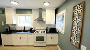 A modern kitchen with white cabinets, a gas stove, and a stainless steel range hood. - Bright Bungalow steps from Caltech & PCC, Close to the Rose Bowl, Kingsize Bed! (Pasadena)