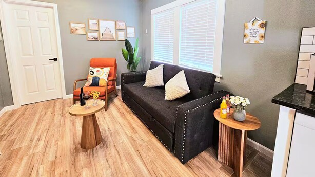 A living room with a black sofa, a wooden coffee table, and a small side table with a vase. - Bright Bungalow steps from Caltech & PCC, Close to the Rose Bowl, Kingsize Bed! (Pasadena)