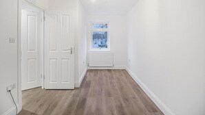 Un pasillo con paredes blancas y suelo de madera, que conduce a una ventana con vistas a un paisaje nevado.