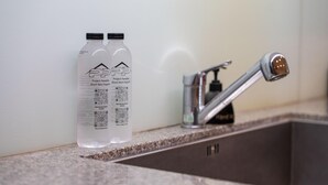 Two bottles with labels and QR codes on a granite countertop next to a modern faucet. - Modern 2BR Surin Beach Condo Pool · Walk to Beach (Surin)