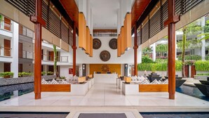 A modern hotel lobby with a reception desk, seating areas, and a pool. - Modern 2BR Surin Beach Condo Pool · Walk to Beach (Surin)