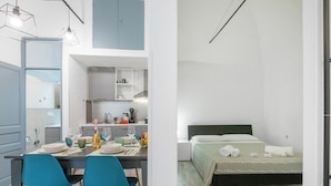 A modern kitchen with a dining area, a bed with a green bedspread, and a small bathroom. - Saro House, Centre Apartment for 6, Sanremo, Italy (Sanremo)