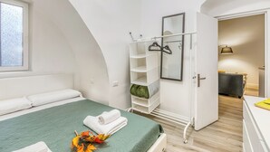 A bedroom with a green bedspread, white pillows, a white wardrobe, and a mirror. - Casa di Lilo Sanremo Historic Center Apartment | Sleeps 4 | A/C, Sanremo, Italy (Sanremo)