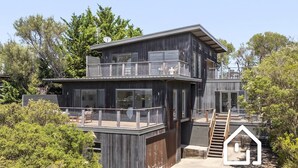 Ein modernes, zweistöckiges Gebäude mit Balkon, Treppe und einer kleinen Terrassenfläche.