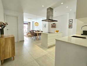 A modern kitchen with a central island, white cabinetry, and a built-in stove. - Maestranza Oasis Marbella by Lica Homes (Marbella)