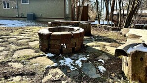 A brick fire pit in a yard with a house in the background. - Habart Retreat - Country Living at its Best (Golden)