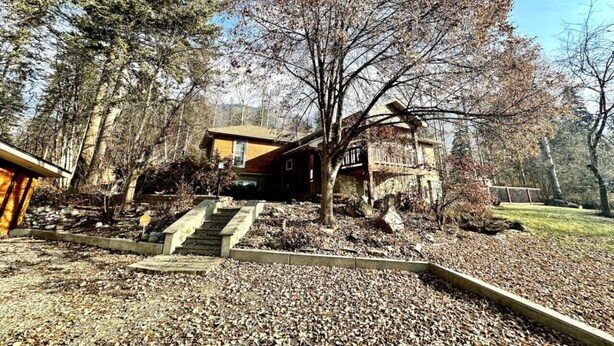 A rustic cabin with a wooden exterior, a stone staircase leading to the entrance, and a surrounding forested area. - Habart Retreat - Country Living at its Best (Golden)