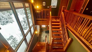 A wooden staircase with a view of snow-covered trees outside. - Creekside Family Hideout @ KHMR - Ski in/Ski Out (Golden)