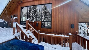 A wooden cabin with a large window, a wooden staircase, and a snow-covered deck. - Creekside Family Hideout @ KHMR - Ski in/Ski Out (Golden)