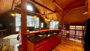 A spacious kitchen with a large island, wooden ceiling beams, and large windows providing natural light. - Creekside Family Hideout @ KHMR - Ski in/Ski Out (Golden)