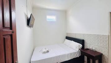 A small, clean room with a single bed, a small table, and a window.