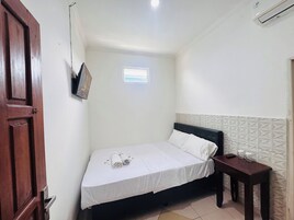 A small, clean room with a single bed, a small table, and a window.