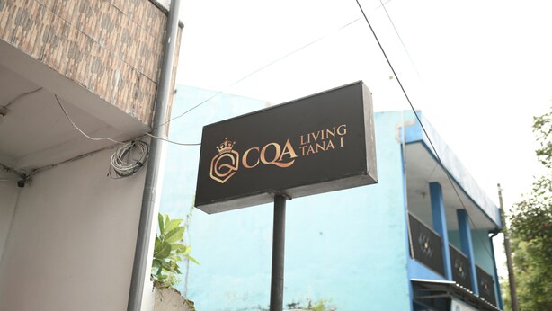 Schild für "COA Living Tana I" mit einem modernen Gebäude im Hintergrund.