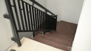 Eine Treppe mit einer schwarzen Metallreling und braunen Stufen.