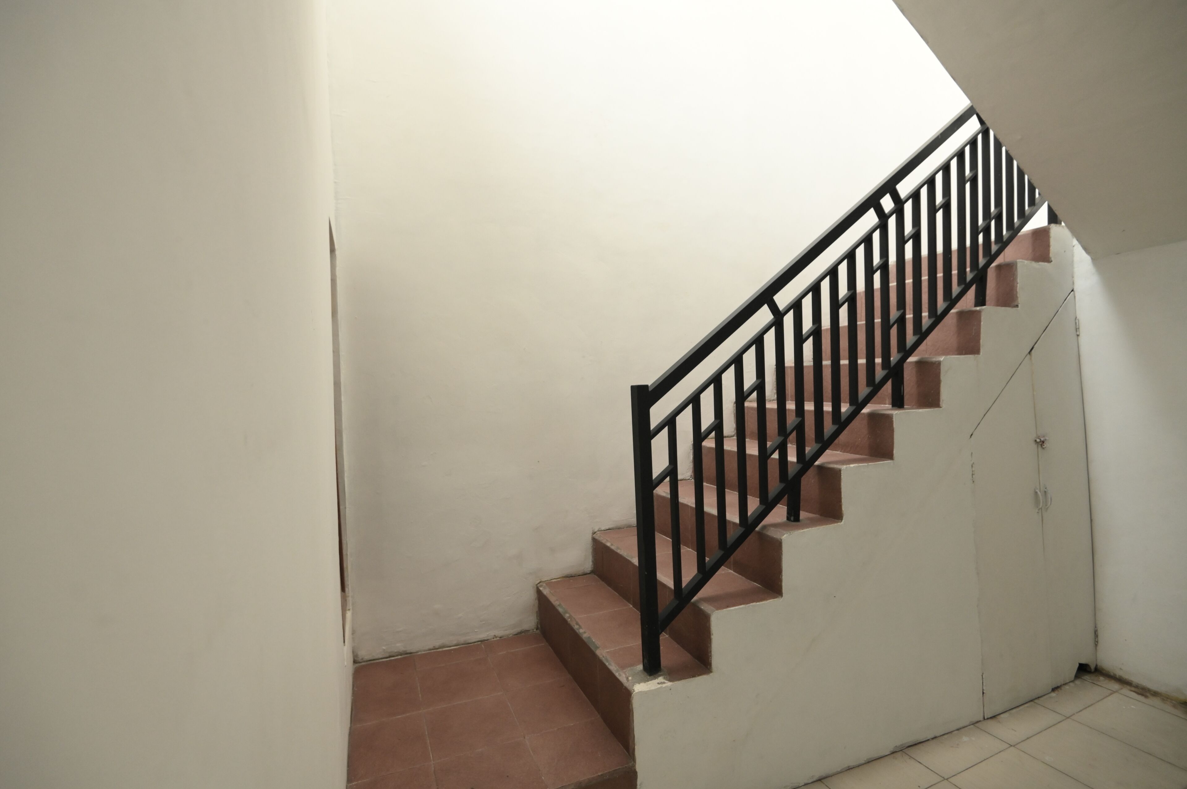 A staircase with black railings and a white wall.