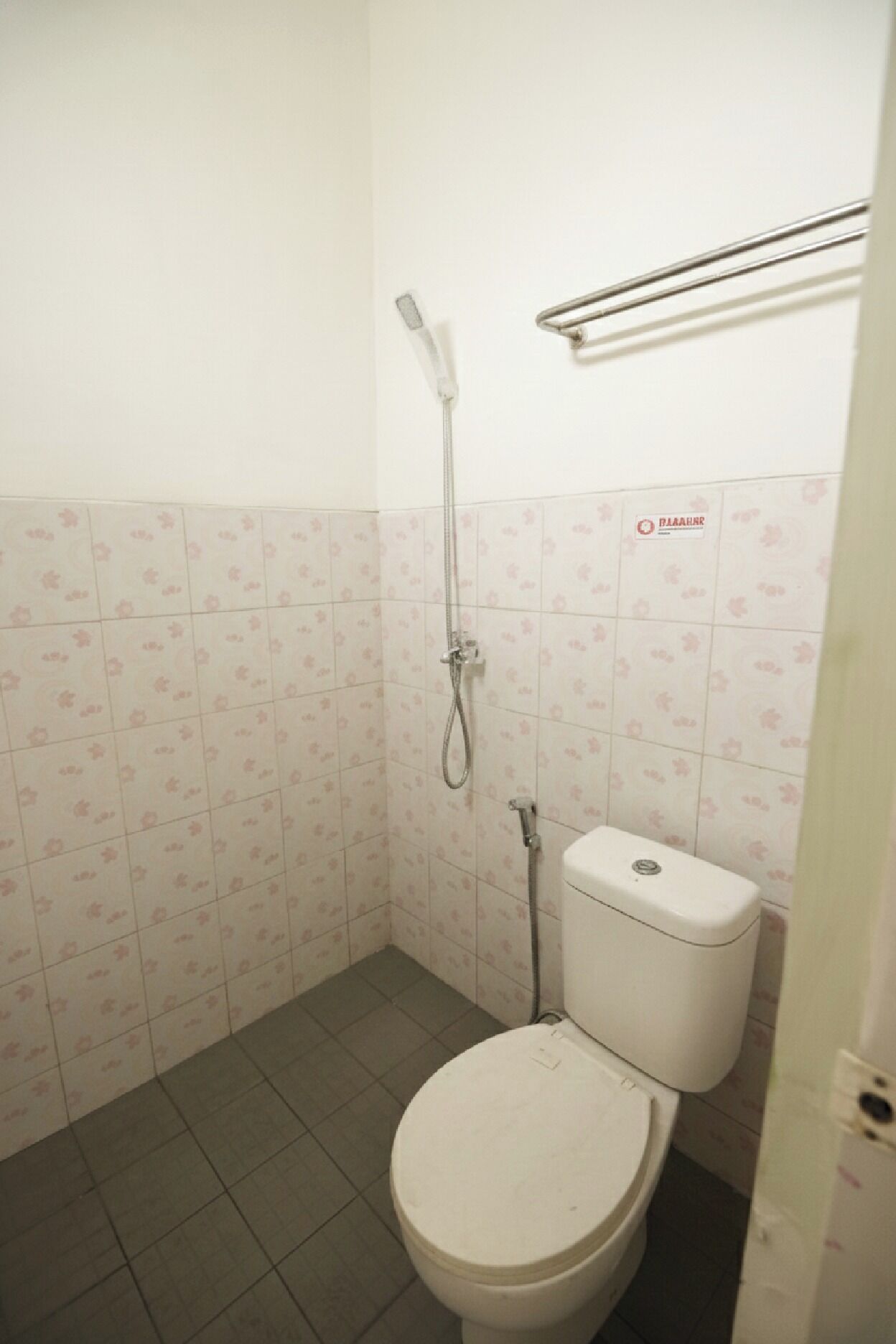 A small bathroom with a toilet, a shower, and a tiled floor.
