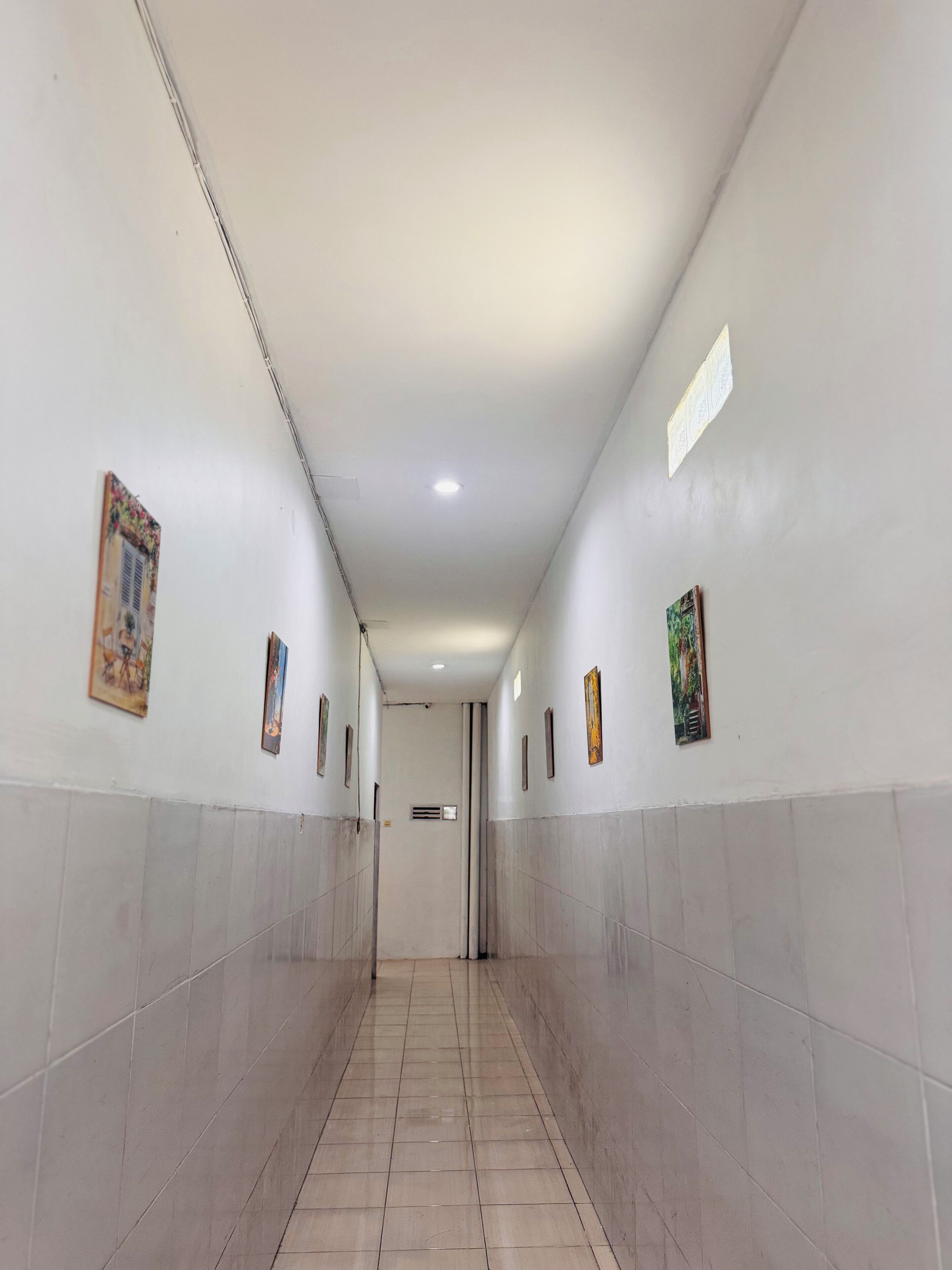 A corridor with tiled walls and a tiled floor, leading to a door at the end.