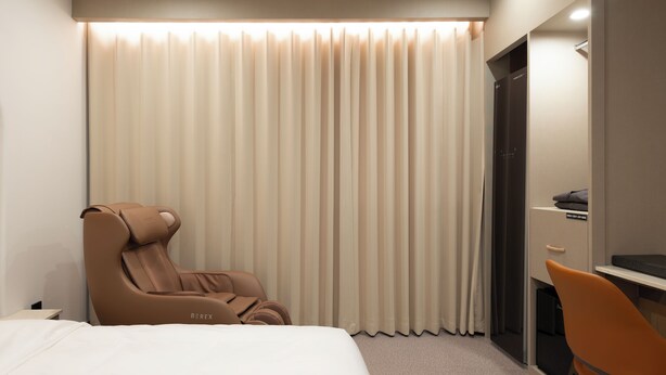 A hotel room with a bed, a massage chair, a desk, and a curtain. - Urban Brown Hotel (Cheongju)