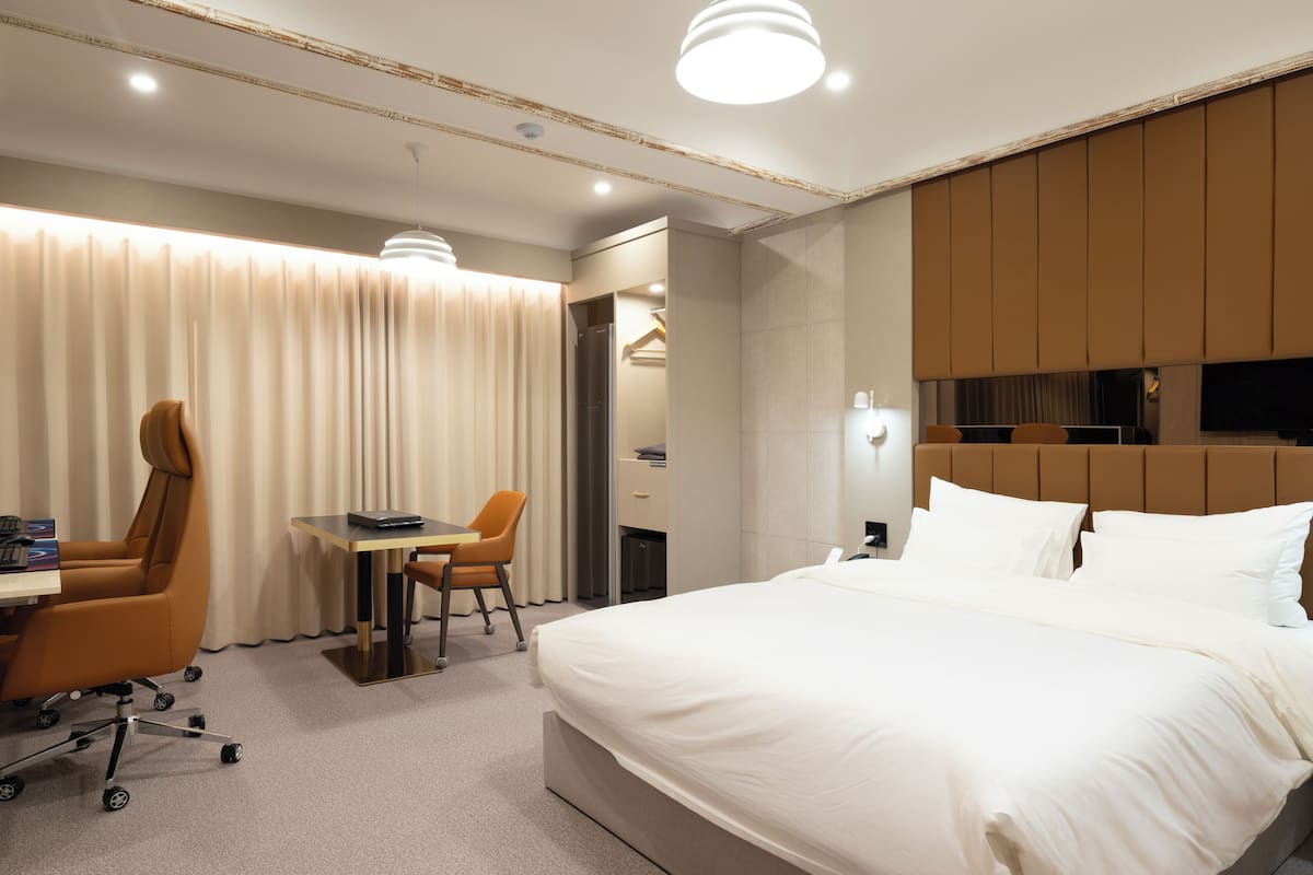 A modern hotel room with a large bed, a desk with a chair, and a television.