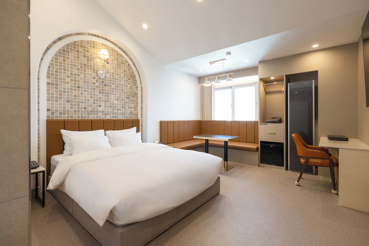 A modern hotel room with a large bed, a seating area, and a desk.