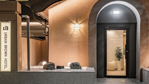L'ingresso di un hotel con facciata in pietra, un arco ad arco e un cartello con la scritta "URBAN BROWN HOTEL".