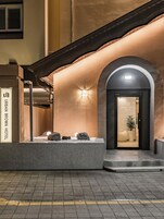 Entrada de un hotel con fachada de piedra, un arco de entrada y un cartel que dice "URBAN BROWN HOTEL".