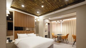 Una moderna camera d'albergo con un letto grande, una scrivania con due sedie, una televisione e un soffitto in legno.
