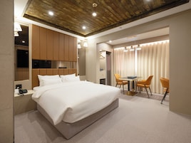Una habitación de hotel moderna con una cama grande, un escritorio con dos sillas, un televisor y techo de madera.