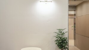 Un interno moderno con un tavolo rotondo e due sgabelli, una pianta in vaso e un lampadario a parete.
